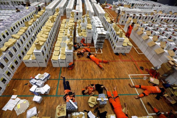 1218434-checknews-workers-lay-during-a-break-as-they-prepare-election-materials-in-a-warehouse-in-jakarta