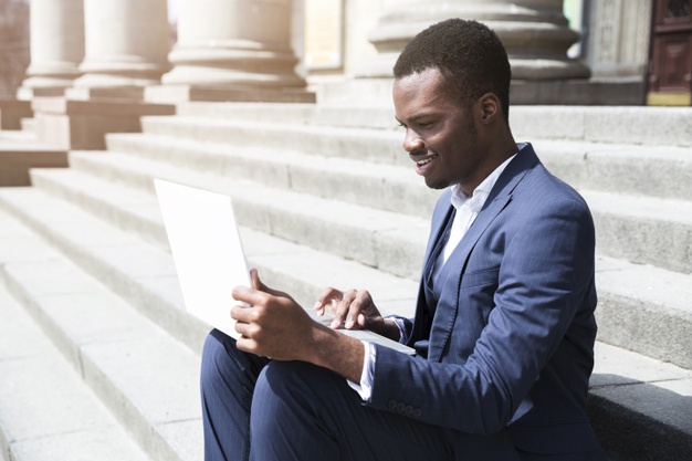 jeune-homme-affaires-africain-assis-marches-aide-ordinateur-portable-exterieur_23-2148190765