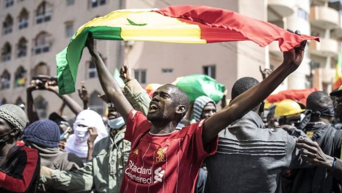 un-homme-brandissant-un-drapeau-du-senegal-lors-d-une-manifestation-a-dakar-le-8-mars-2021_6296706