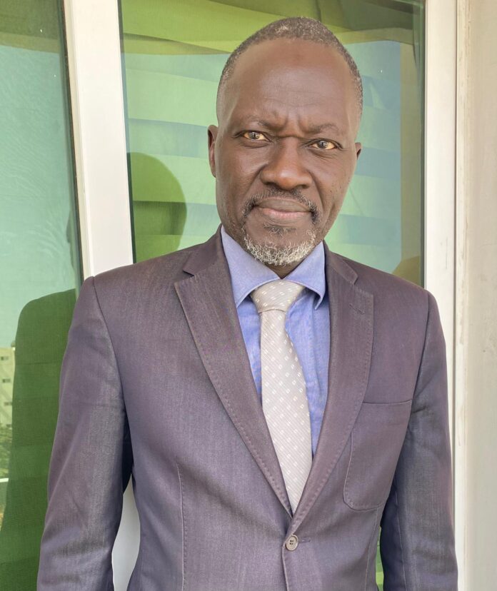 Ousseynou Nar Gueye veste jean cravate grise gros plan
